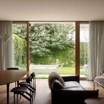 Side garden profile showing planting softening the modern brick facade of the Silver House extension.